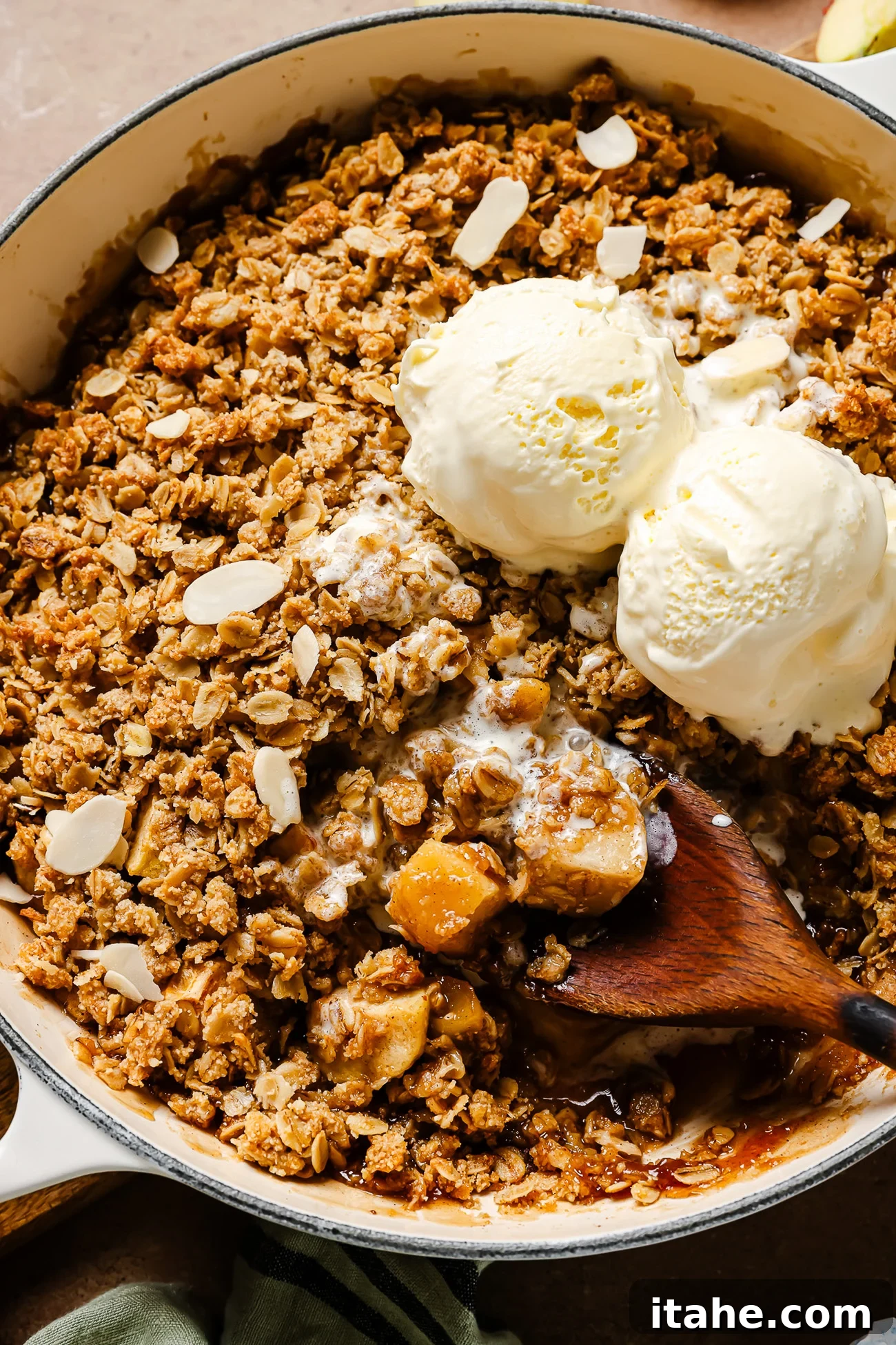 Closeup view of gluten-free apple crisp with vanilla ice cream on top, ready to be served.
