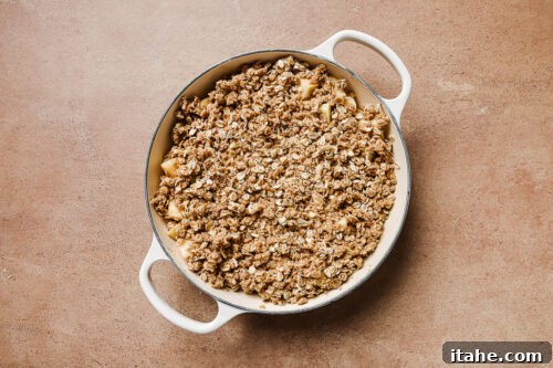 Gluten-free apple crisp in a white skillet, ready to go to the oven.