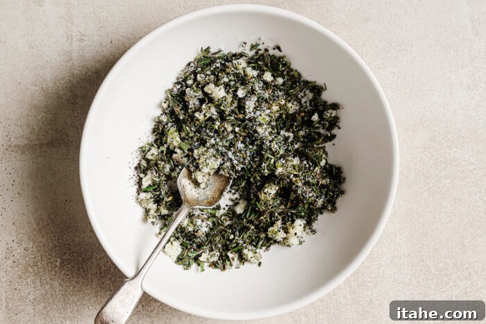 Fresh herbs and seasoning in a white bowl, ready to rub over the prime rib for roasting.