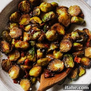 Overhead view of maple bacon Brussels sprouts in a white platter, coated in a sweet maple glaze with crispy bacon pieces.