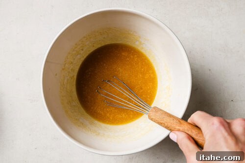 Rich pecan pie brownie batter in a white mixing bowl, ready to be poured into the pan for baking.