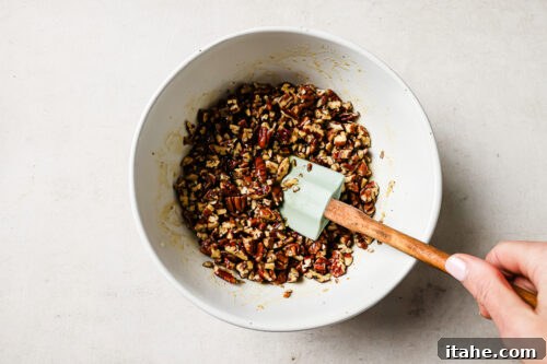 Pecan pie topping mixture in a white bowl with a spatula.