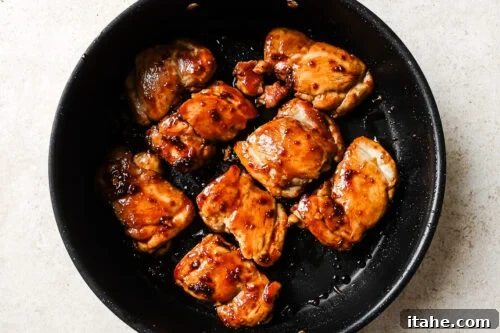 Cooked chicken thighs simmering in honey garlic sauce in a skillet
