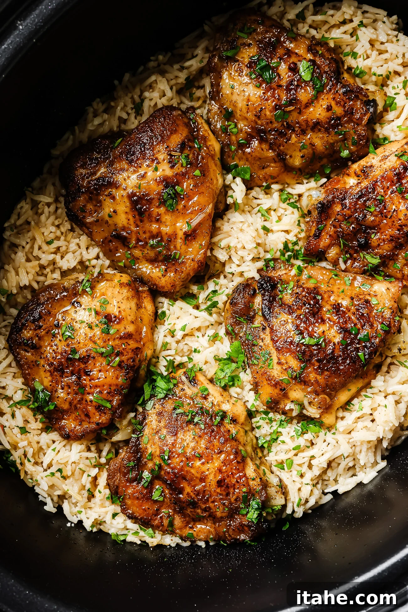 Closeup of succulent slow cooker chicken and rice, garnished with fresh herbs, ready to be served from the pot.