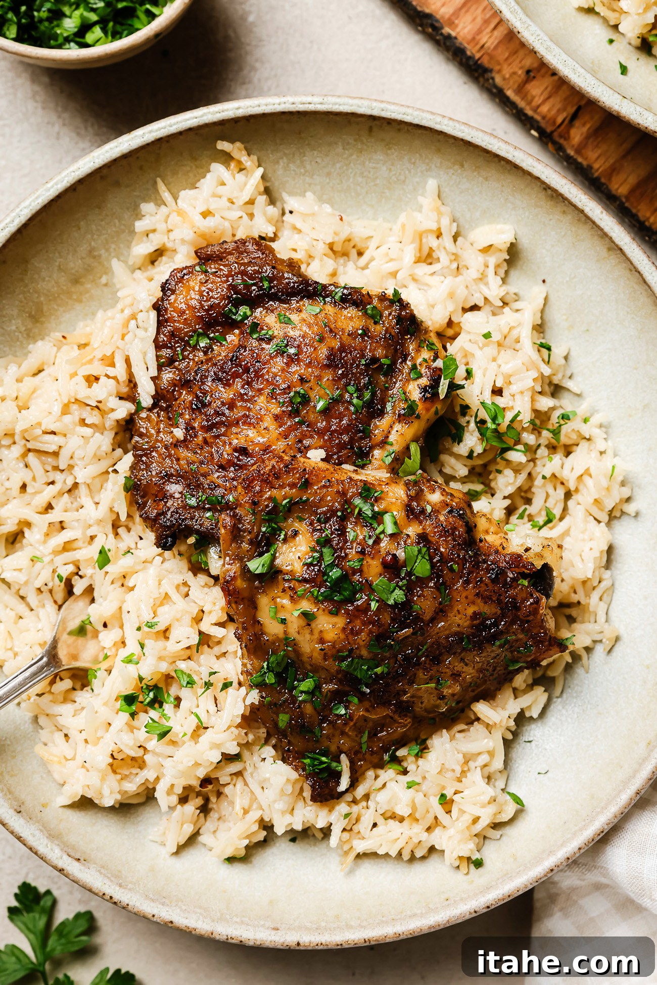 Closeup of a serving of slow cooker chicken and rice on a white plate, garnished with fresh parsley.