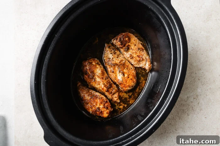 closeup of slow cooker chicken breast inside of a slow cooker. 