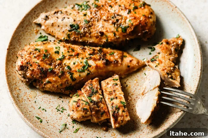 Slow cooker chicken breasts served on a plate with a fork.