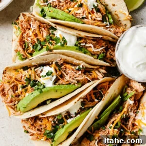 Slow Cooker Chicken Tacos with fresh toppings on a kitchen countertop.
