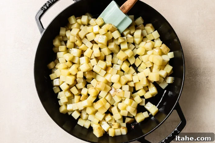 Overhead view of diced raw potatoes in a cast-iron skillet, ready for cooking.