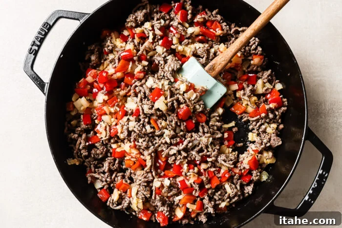 Overhead view of cooked ground beef and vegetables in a cast-iron skillet.