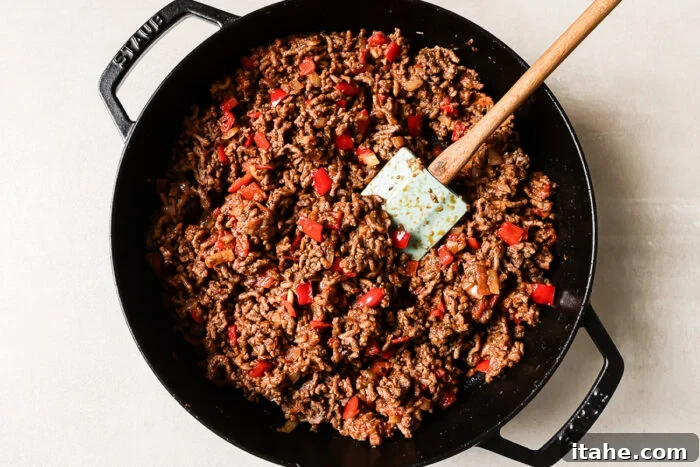 Overhead view of cooked ground beef and vegetables in a cast-iron skillet.