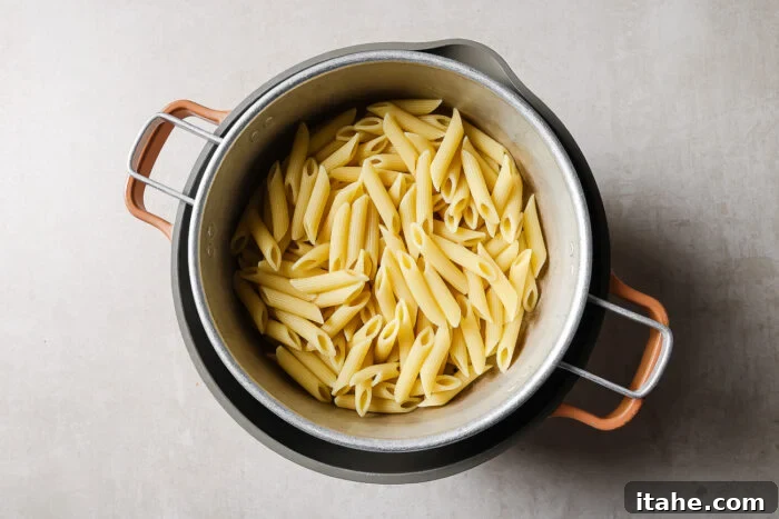 Creamy Marry Me Chicken Pasta Recipe 4 A pot filled with cooked penne pasta, viewed from above, sitting on a light-colored surface.